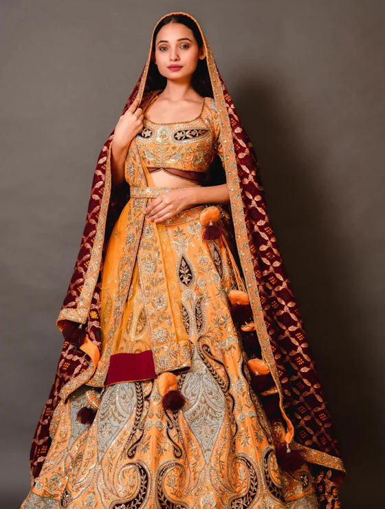 Woman in an ornate yellow and maroon designer lehenga